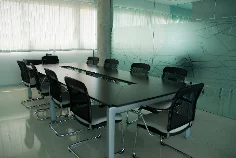 Sala de reuniones vacía con una mesa larga y sillas alrededor