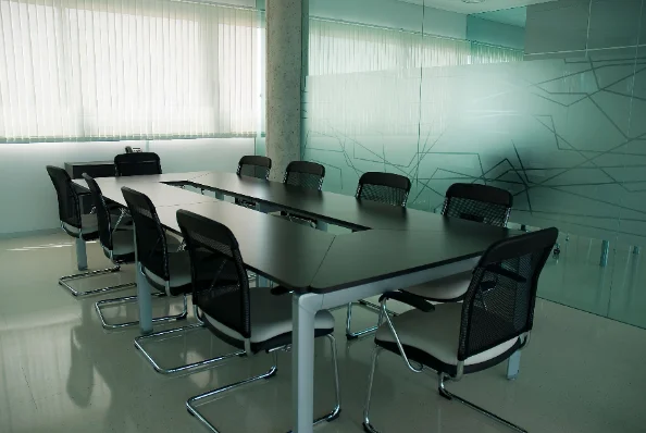 Sala de reuniones vacía con una mesa larga y sillas alrededor