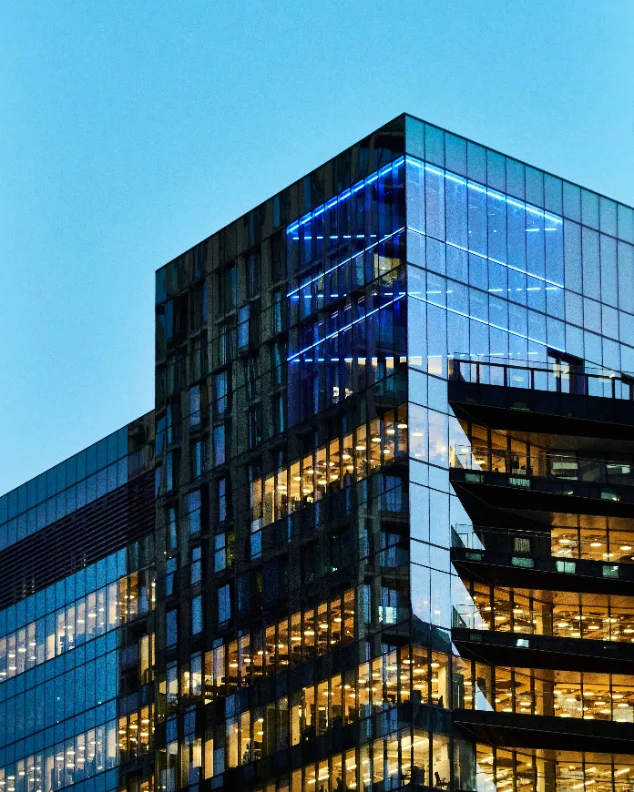 Torre corporativa de oficinas con las luces encendidas al anochecer